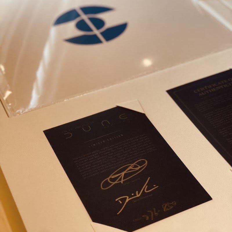 Two black signed cards on a cream surface beside a blue logo sign