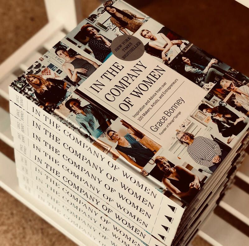 Stack of books titled “In the Company of Women” by Grace Bonney on a beige surface.