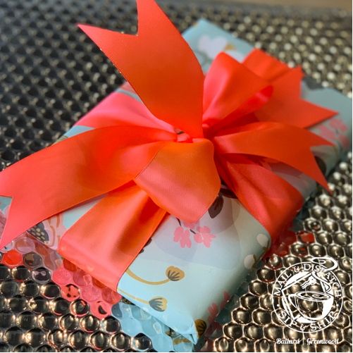 Small wrapped gift with a bright red bow on a patterned surface