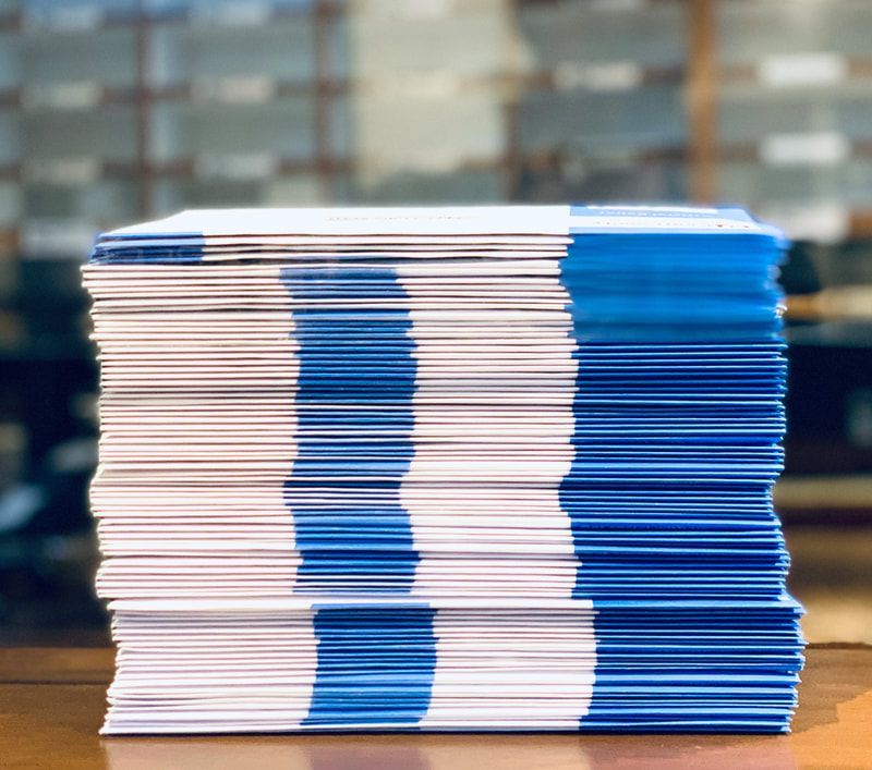 Stack of blue-and-white folded papers on a table with a blurred office background