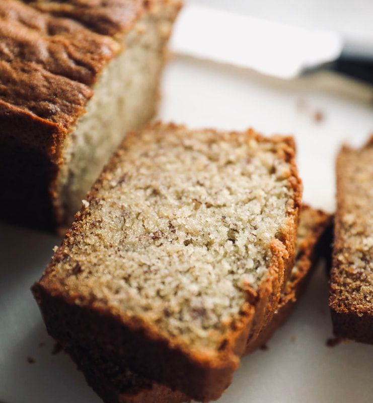 Sliced loaf cake with a golden-brown crust and moist crumb on a white surface