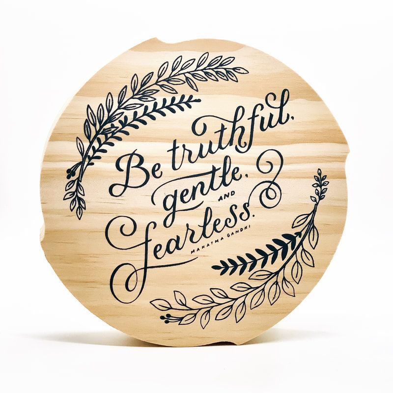 Round wooden sign with black script: “Be truthful, gentle, fearless,” framed by leafy wreaths.
