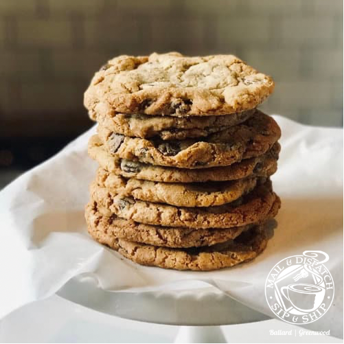 Stack of oatmeal cookies on a white plate, with one cookie broken on top, against a blurred background