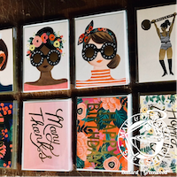 Assorted colorful greeting cards with illustrated faces and hand-lettered messages arranged in a grid.