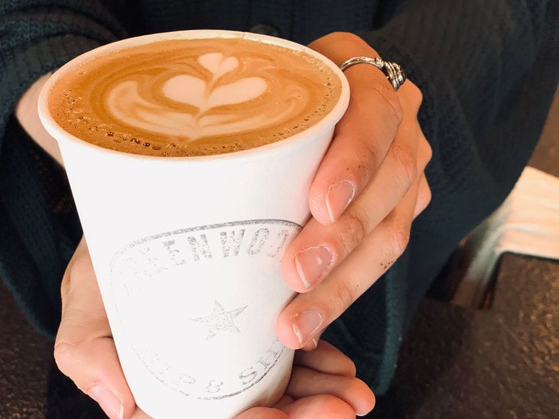 Hands holding a white cup of latte with heart latte art
