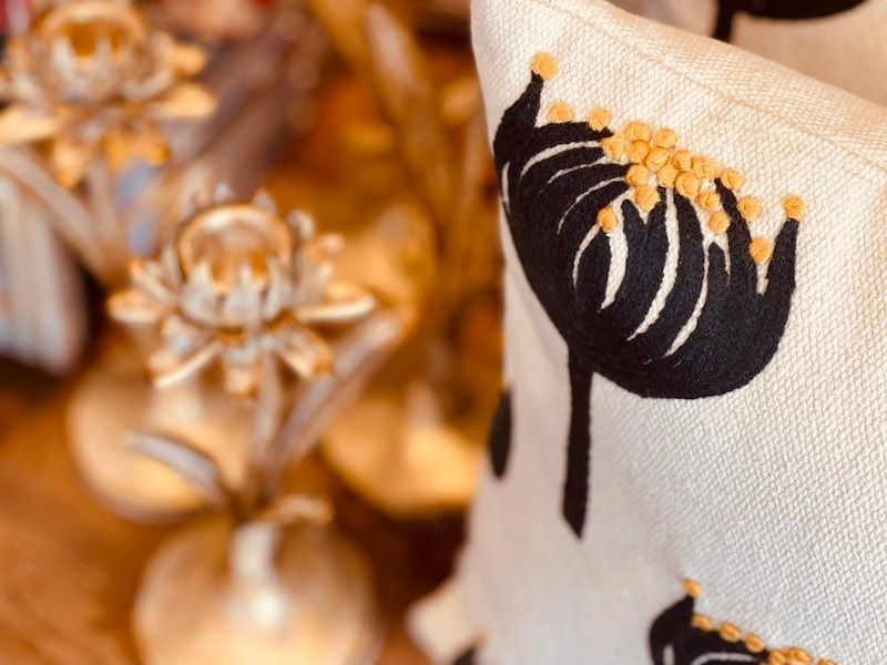 Black flower print on cream fabric beside soft-focus golden floral decor
