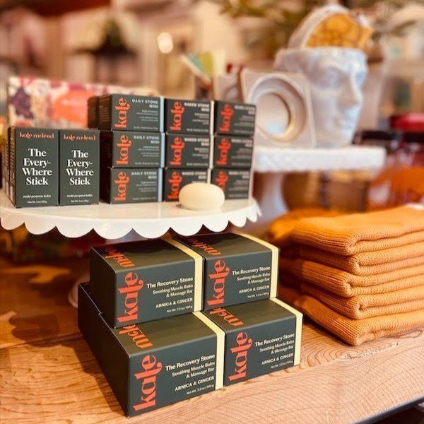 Gift display with stacked black boxes and folded orange towels on a white shelf.