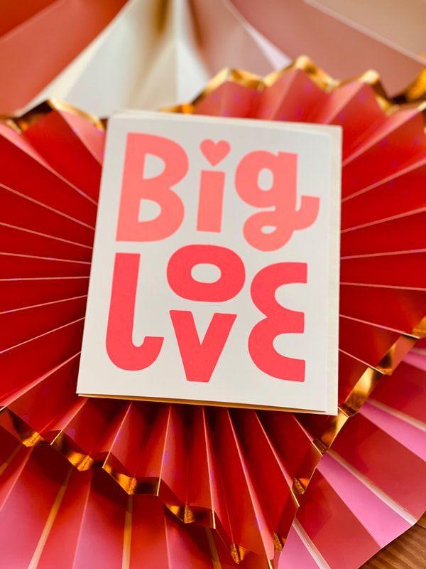 Red gift box with pink “Big Love” text on a red and gold paper fan background