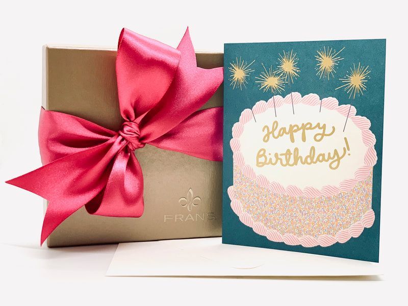 Pink ribbon gift box beside teal happy birthday card with cake illustration