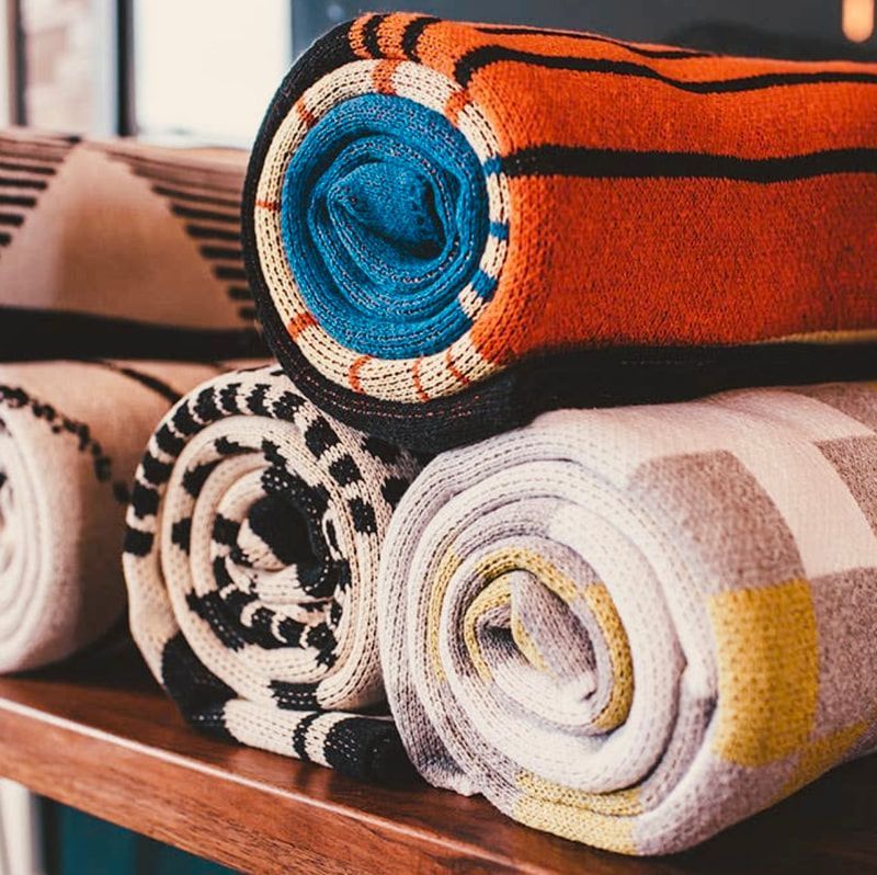 Rolled colorful patterned blankets stacked on a wooden shelf