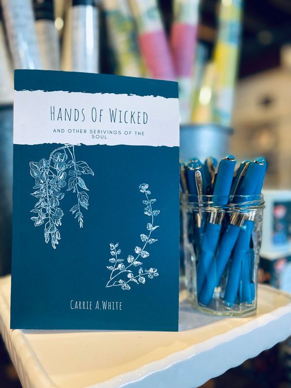 Teal witchcraft notebook beside a glass jar of blue pens on a desk