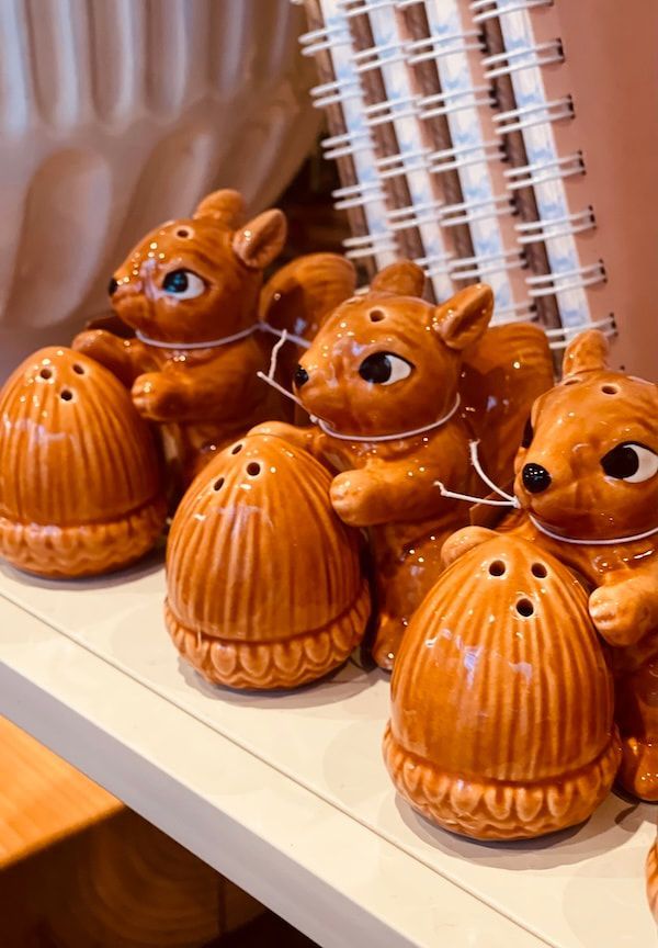 Orange bear-shaped ceramic containers on a shelf beside a spiral notebook