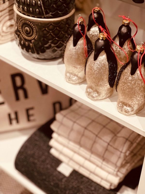 Shelf with folded towels and decorative penguin figurines in a store display