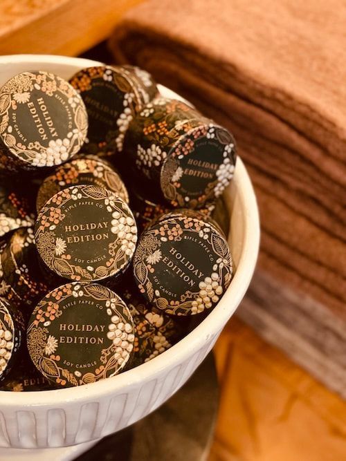 Bowl of wrapped holiday edition chocolates beside stacked brown napkins