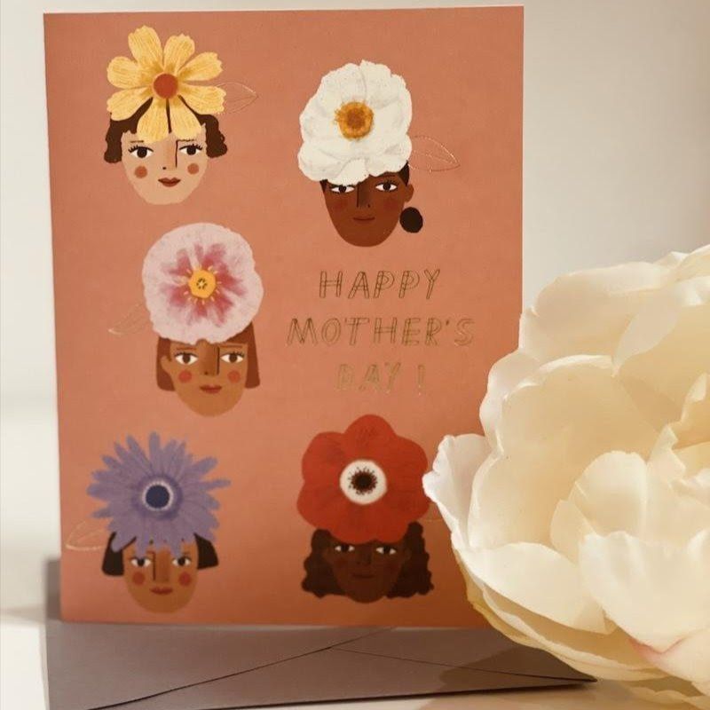 Mother’s Day card with four flower-crowned faces and “Happy Mother’s Day” text beside a white flower.