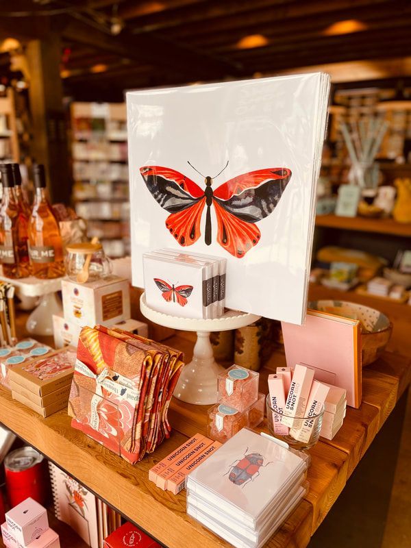 Butterfly-themed display of notebooks, cards, and gift items on a wooden table in a shop