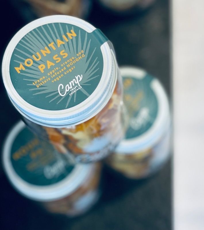 Top-down view of three stacked Mountain Pass canned drinks with teal lids and orange accents