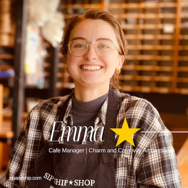 Smiling café manager in glasses and plaid shirt, standing in a warm coffee shop interior