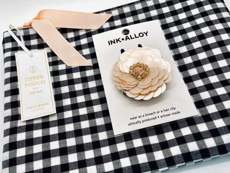 Gingham gift pouch with a cream flower hair clip and a small hanging tag on black-and-white check fabric