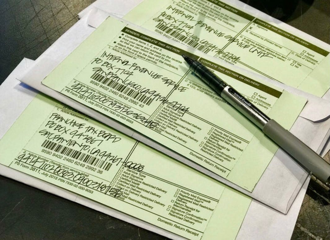 Stack of green forms with a pen on top, arranged on a desk.