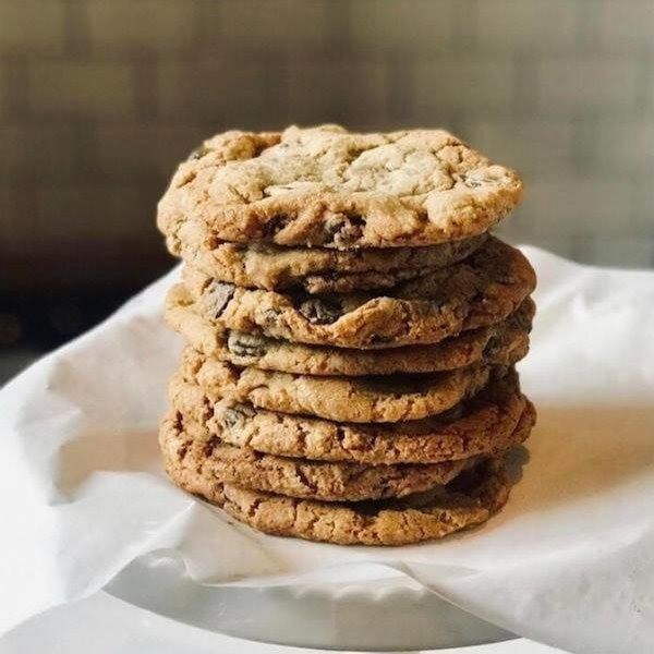 Stack of oatmeal raisin cookies on white parchment paper, with one cookie leaning on top.