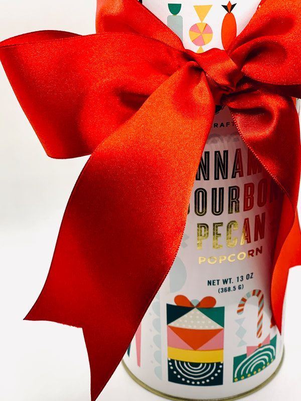 Gift bag with a large red ribbon bow and a colorful popcorn package visible underneath.