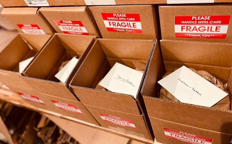 Open cardboard boxes labeled “FRAGILE,” some open with white packing inside.