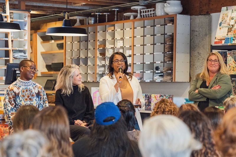 Panel discussion in a café, with a speaker holding a microphone before seated audience members.