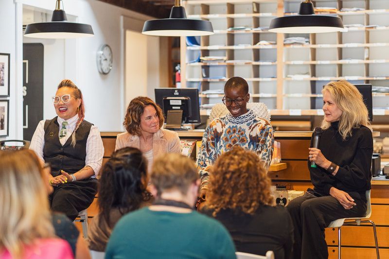 Panel discussion in a café, with four speakers seated on a stage facing an audience.