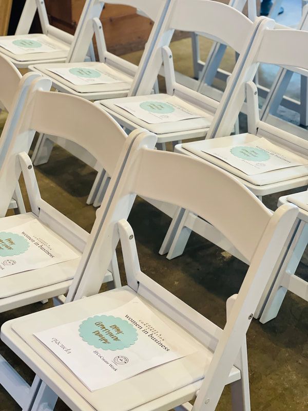 Rows of white folding chairs with programs on the seats, arranged indoors for an event