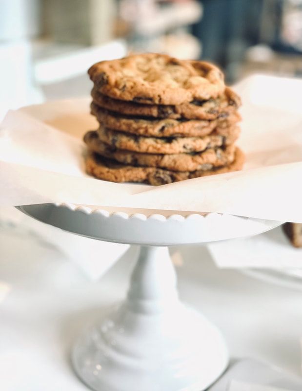 Stack of chocolate chip cookies on a white cake stand with a serving knife in front
