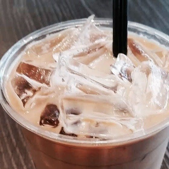 Iced coffee in a clear plastic cup with a black straw and ice cubes