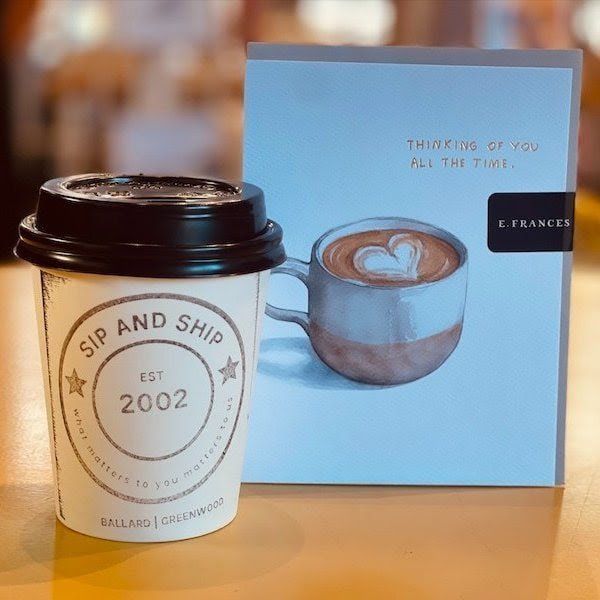 Coffee cup and blue box on a wooden table, with “Sip and Ship” and “Thinking of you all the time” text.