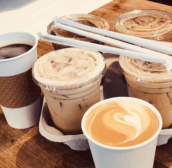 Assorted iced coffees and lattes in takeaway cups on a wooden table