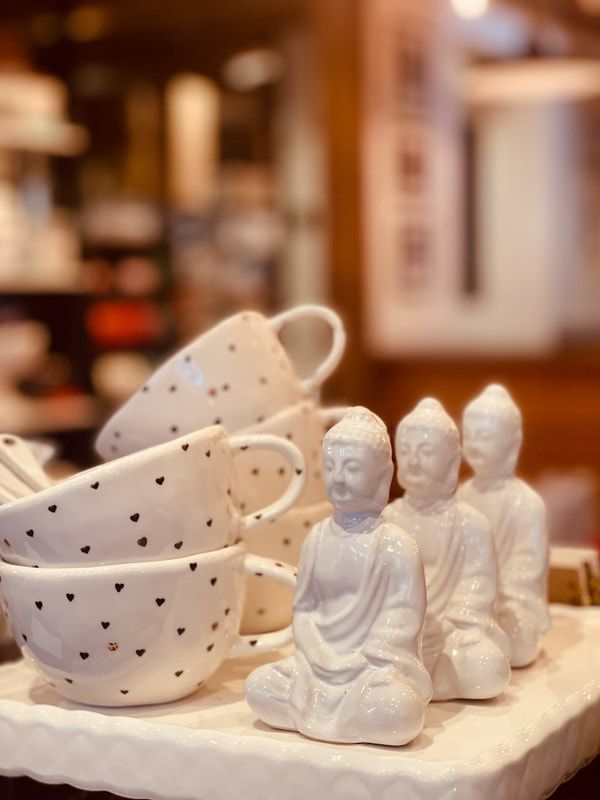 White speckled teacups and small Buddha figurines on a soft cloth tabletop