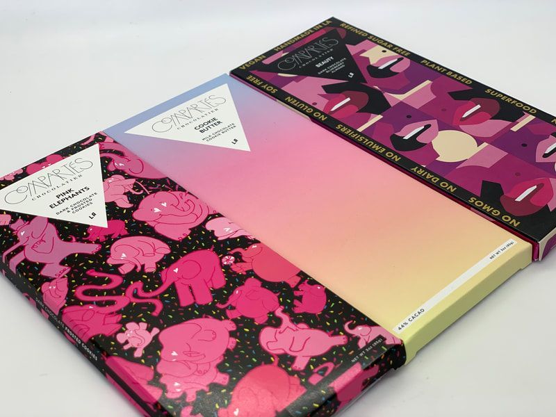 Three colorful patterned notebooks with pink, black, and yellow covers stacked on a white surface