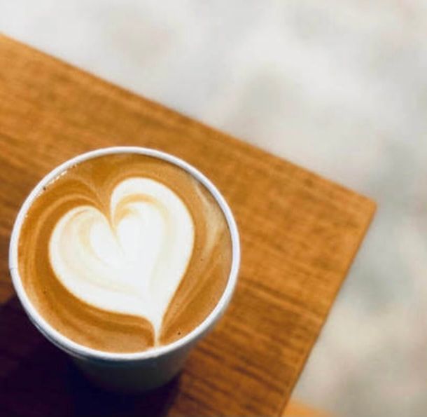 Latte with heart-shaped foam art in a cup on a wooden table
