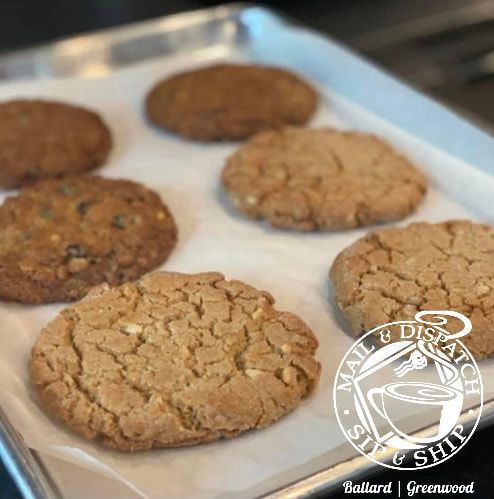 Five baked cookies on a parchment-lined baking sheet, with a watermark in the lower right corner