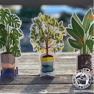 Three colorful potted paper plant cutouts on a sunlit windowsill.