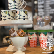 Toc confectionery display with stacked patterned cups and a white bowl holding chocolate bars
