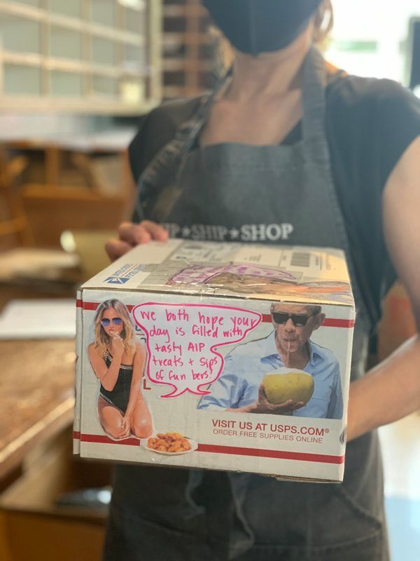 Person holding a boxed pastry with a printed photo and handwritten pink message in a shop setting