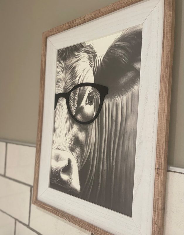 Framed black-and-white cow portrait wearing glasses on a wall