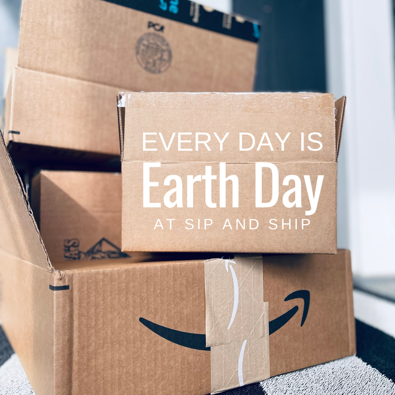 Stacked Amazon boxes with a sign reading “Every Day Is Earth Day at Sip and Ship”