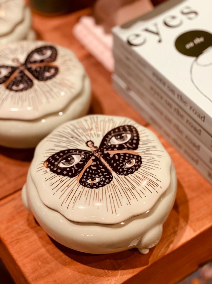 White butterfly-decorated round boxes on a wooden tray beside a stack of matching packaging.
