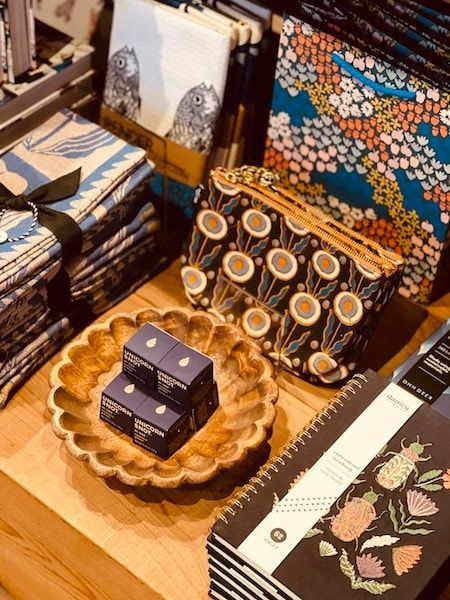 Decorative tabletop display with patterned notebooks, a wooden tray, and small black gift boxes