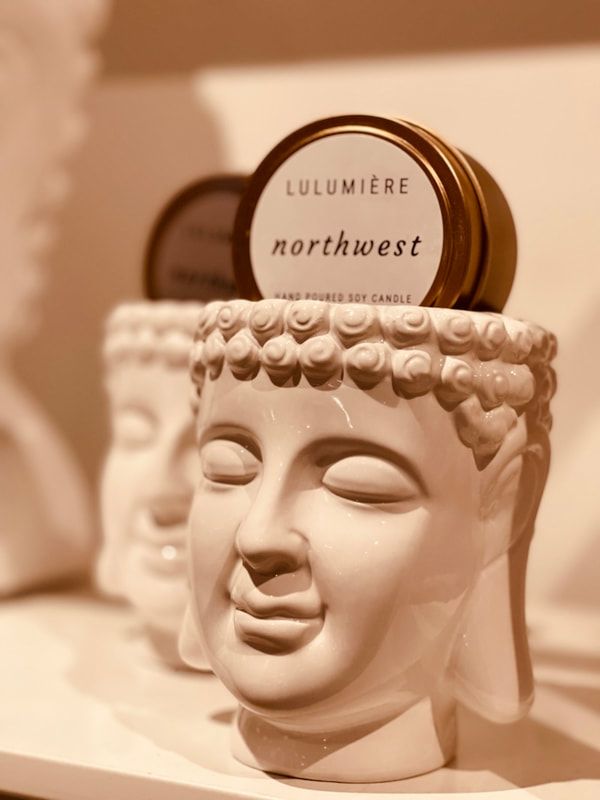 Cream Buddha-shaped candle jar with a round label reading “LULUMIERE northwest”