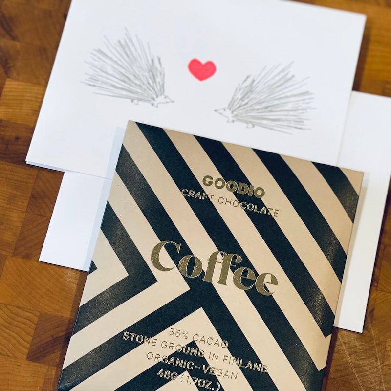 Coffee-themed gift card with black diagonal stripes and a white card with a red heart on a wooden surface