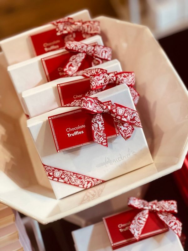 Red gift boxes with white patterned bows arranged in a beige tray.