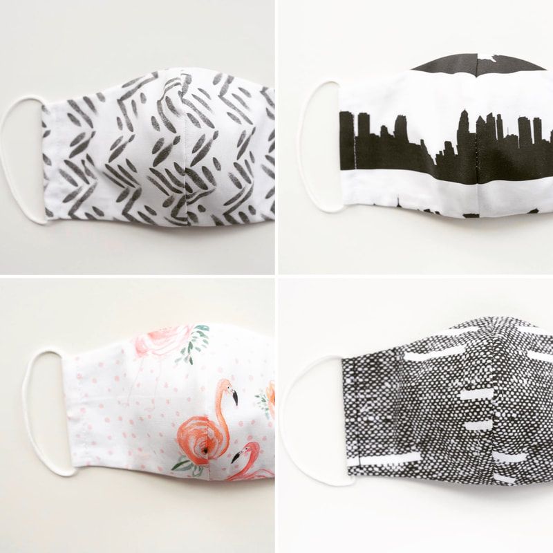 Four patterned cloth face masks in a 2x2 grid, showing black, white, and orange designs