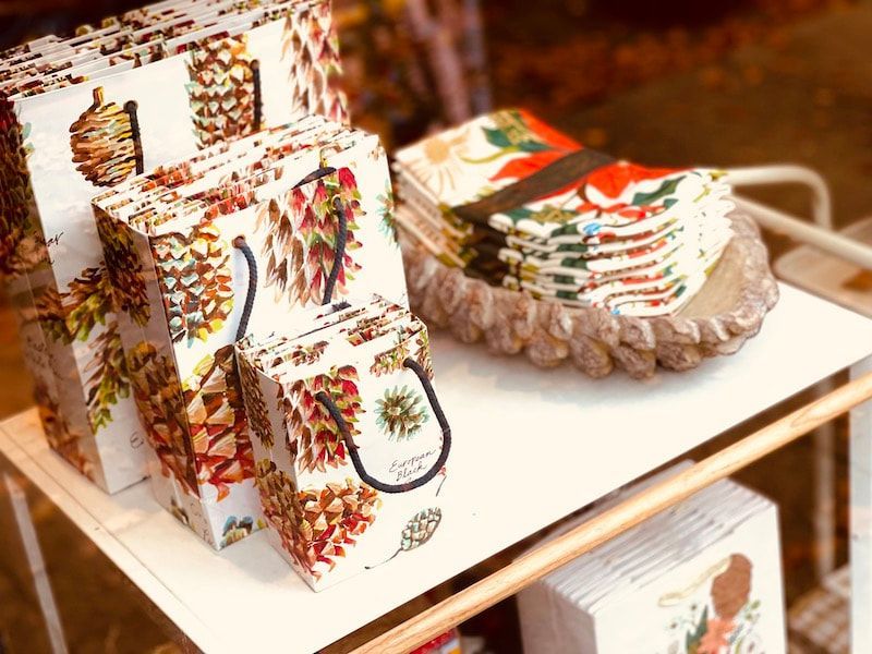 Handmade colorful woven baskets and bags displayed on a white shelf in a craft shop